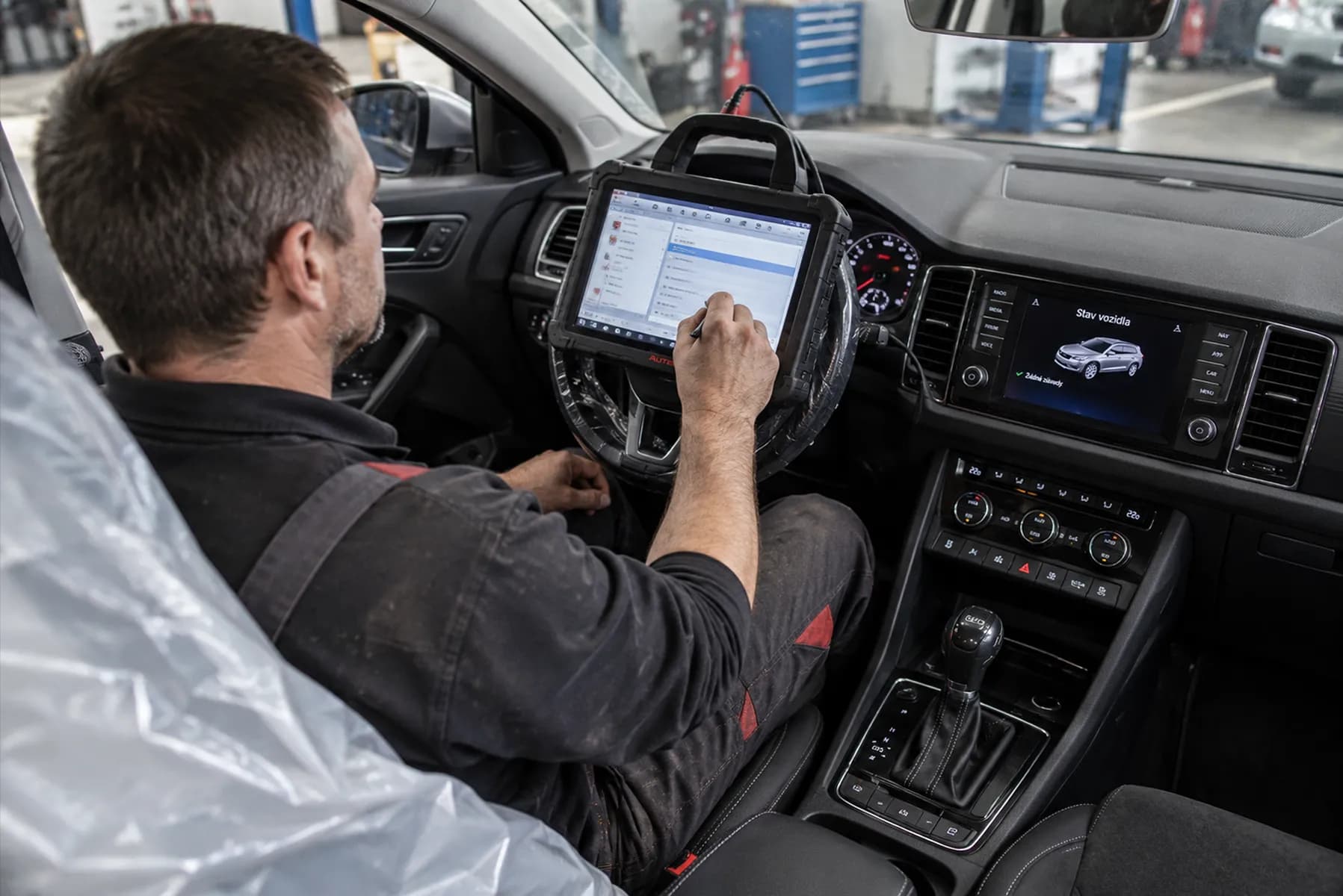 Mechanik používá diagnostický tablet v interiéru vozu