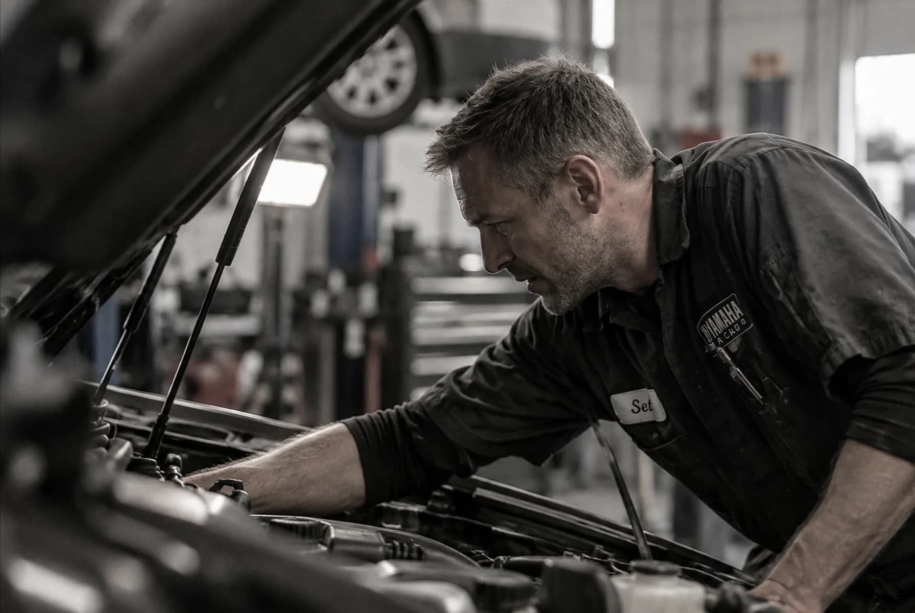 Černobílý portrét mechanika při práci v motorovém prostoru